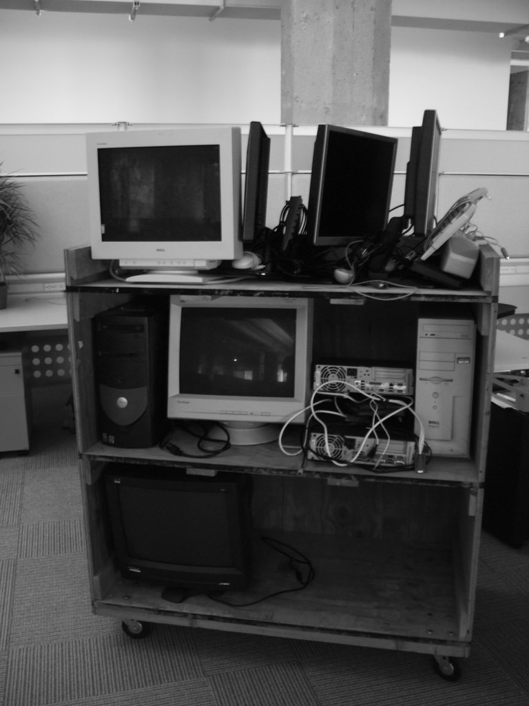 A rolling cart with several computers stacked up